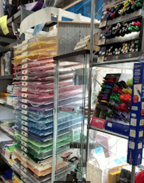 Estantes de papelería con pilas de papel colorido y exhibidores de marcadores y suministros artísticos.
