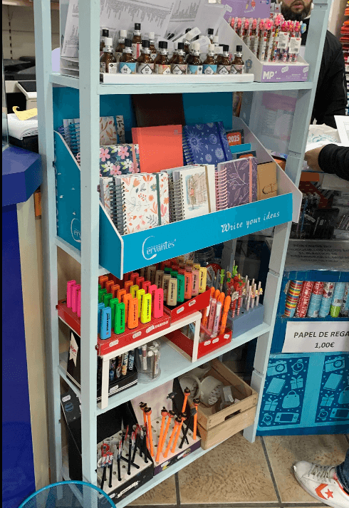 Estantería azul claro llena de cuadernos estampados, resaltadores coloridos y diversos artículos de papelería.